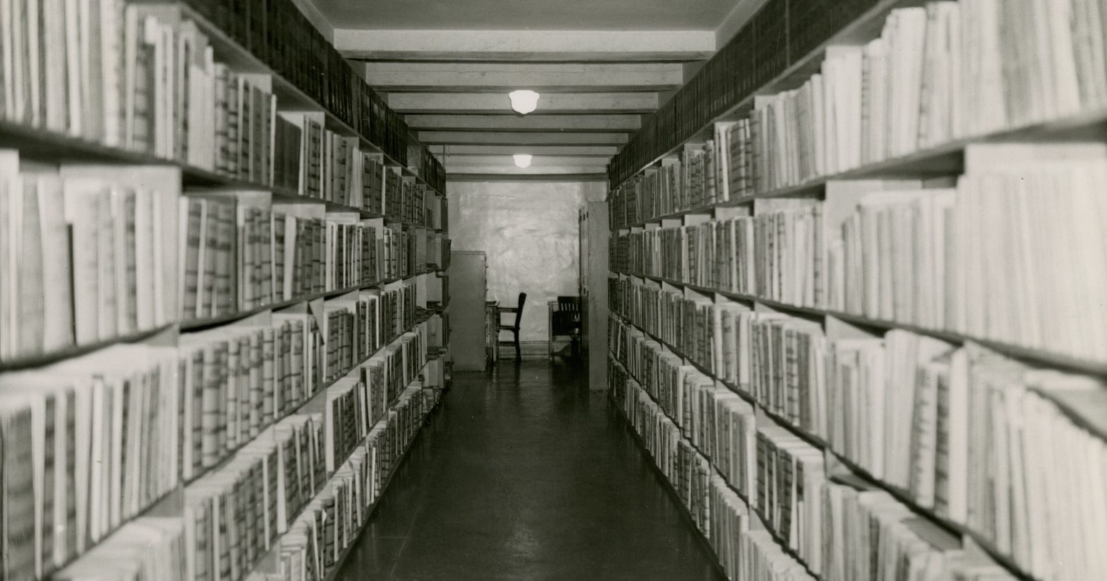 Regały biblioteczne wypełnione oprawionymi tomami — zbiór dokumentacji, którą trzeba przejrzeć przy ocenie.